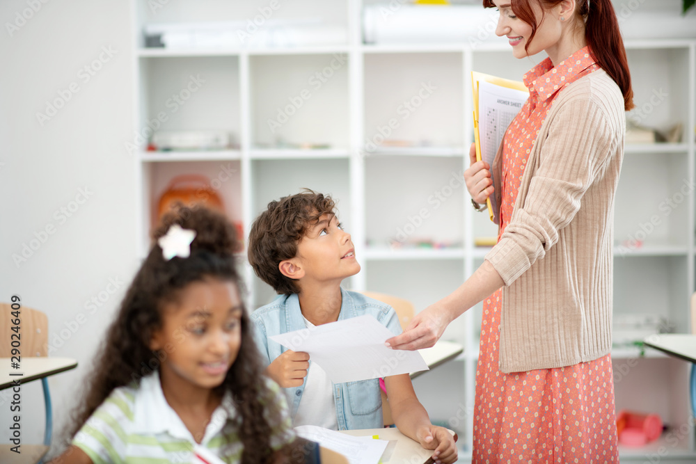 Teacher wearing spotted dress giving test to boy Teacher wearing spotted dress giving test to boy