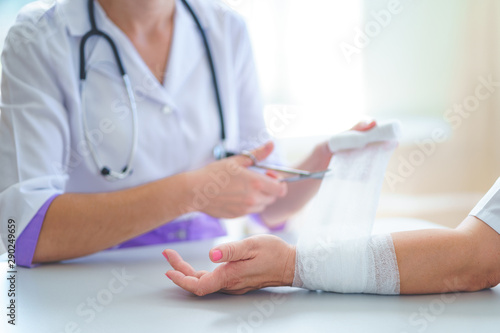 Photography Doctor is bandaging wrist of patient in clinic