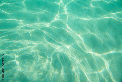 Underwater. Sun glare at the bottom of the seat. Waves underwater and rays of sunlight shining through. Deep turquoise blue sea. Ocean. Transparent water and light at sand.