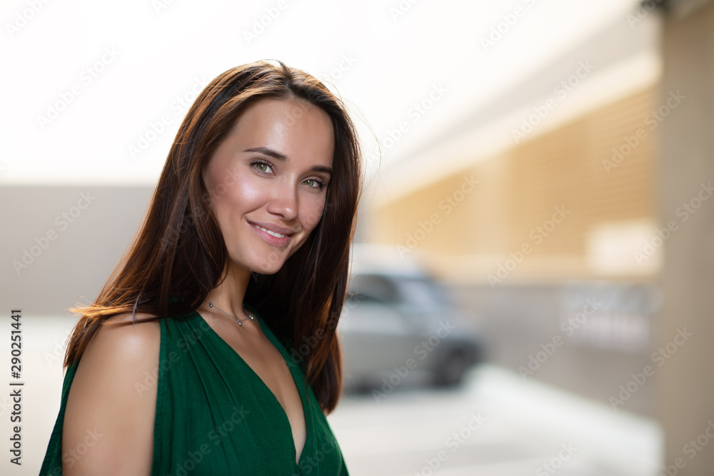 Young pretty likable cheerful woman posing summer city outdoor. Beautiful self-confident girl dressed in emerald-colored jumpsuit with long brown hair walking street enjoing her life, urban lifestyle Young pretty likable cheerful woman posing summer city outdoor. Beautiful self-confident girl dressed in emerald-colored jumpsuit with long brown hair walking street enjoing her life, urban lifestyle
