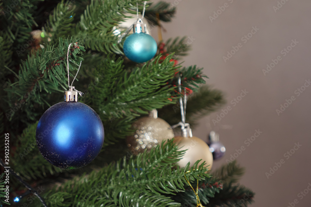 blue christmas decorative toy ball hangs on artificial green tree branch, close up blue christmas decorative toy ball hangs on artificial green tree branch, close up
