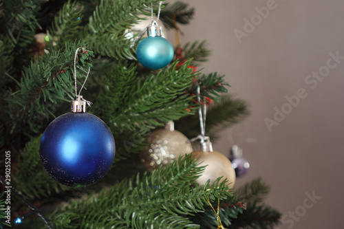 blue christmas decorative toy ball hangs on artificial green tree branch, close up