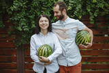 Portrait of a happy couple with a watermelon in their hands. Wooden background.