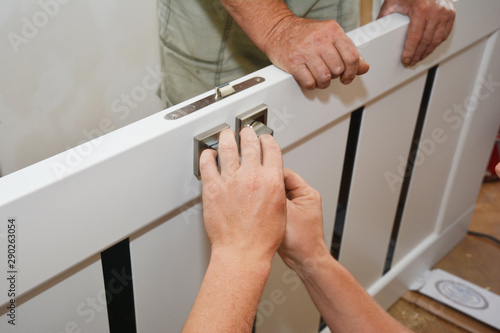 Contractors installing door handle and lock in new white house door