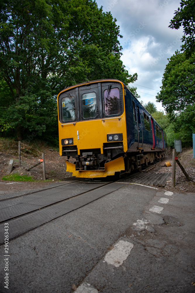 Railway train approaching an unmanned level crossing an a small branch line near Calstock in Cornwall.