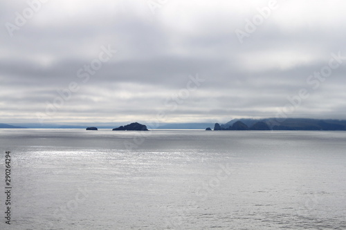 White calm waters of cape Horn in the South Atlantic. Cold waters near Antarctica. Some islands in the horizon and cloudy gray sky.