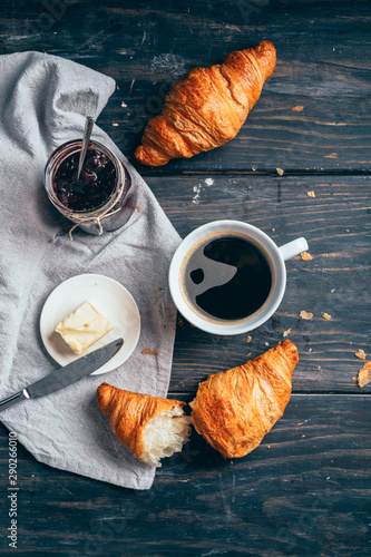 top angle view of croissants, coffee and butter on dark wooden table with copyspace