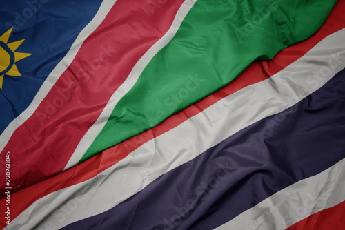 waving colorful flag of thailand and national flag of namibia.
