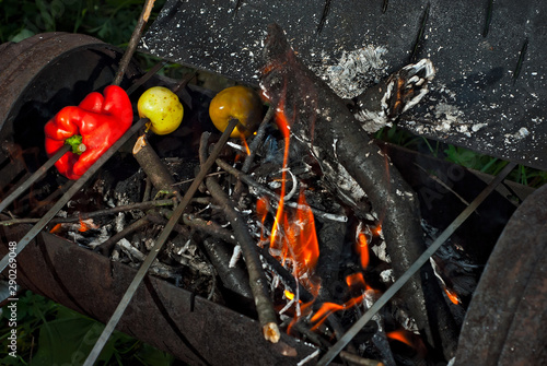 Grilled vegetables are baked on fire. The apples and peppers are roasting in the evening.