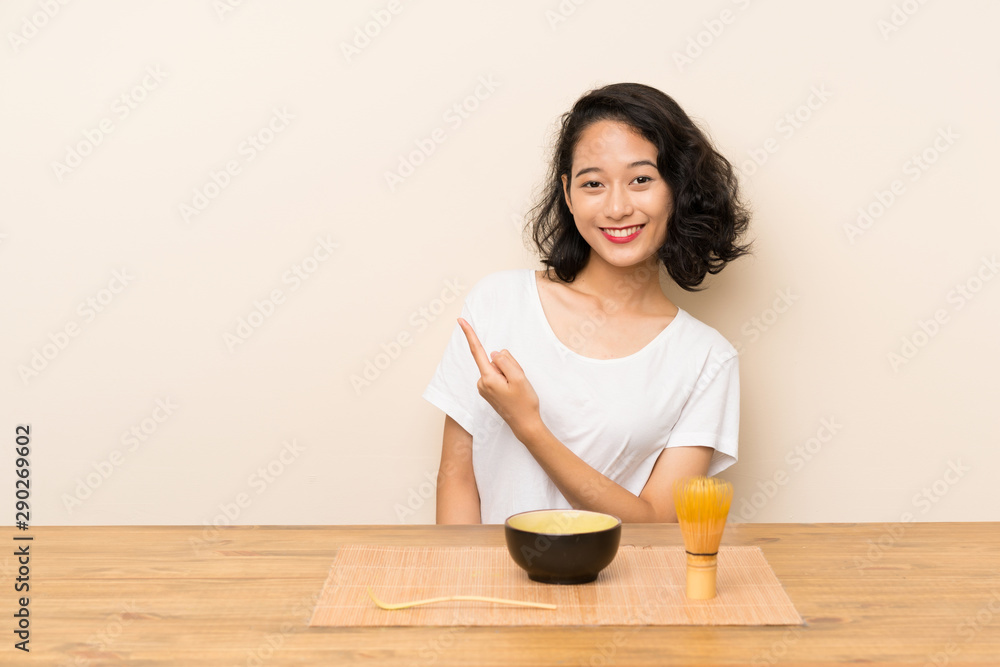 Young asian girl with tea matcha pointing to the side to present a product Young asian girl with tea matcha pointing to the side to present a product