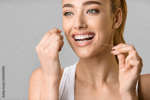Tooth care. Young woman using dental floss
