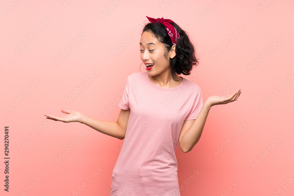 Asian young woman over isolated pink background holding copyspace with two hands Asian young woman over isolated pink background holding copyspace with two hands