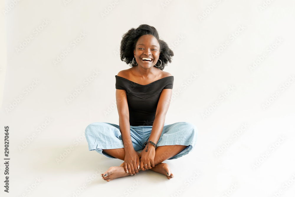 Young black woman with afro hairstyle smiling. Girl wearing black. Studio shot. Young black woman with afro hairstyle smiling. Girl wearing black. Studio shot.