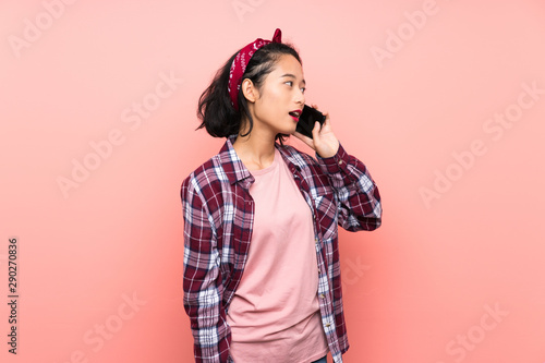 Asian young woman over isolated pink background keeping a conversation with the mobile phone © luismolinero