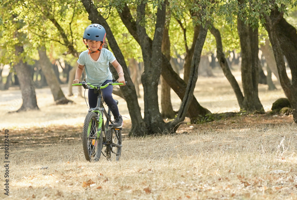 Children girl riding bicycle in forest