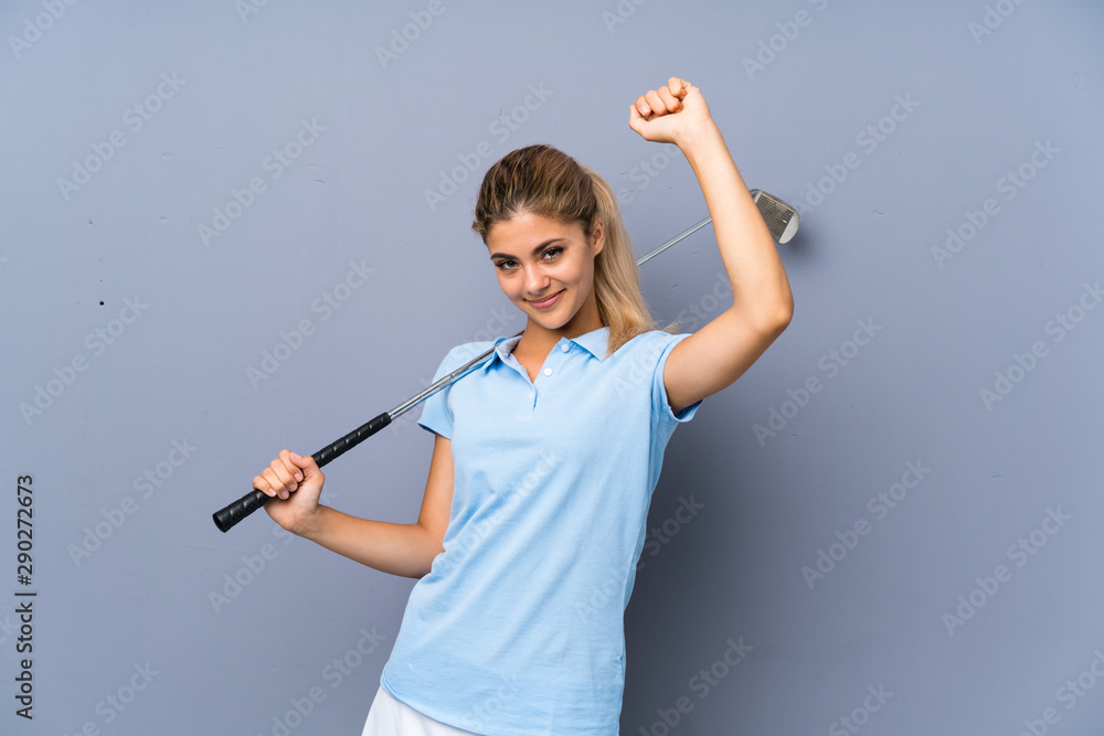 Teenager golfer girl over grey wall celebrating a victory Teenager golfer girl over grey wall celebrating a victory