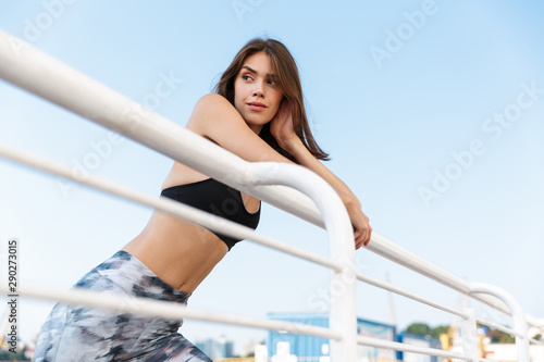 Image of seductive confident woman looking aside while bending on railing © Drobot Dean