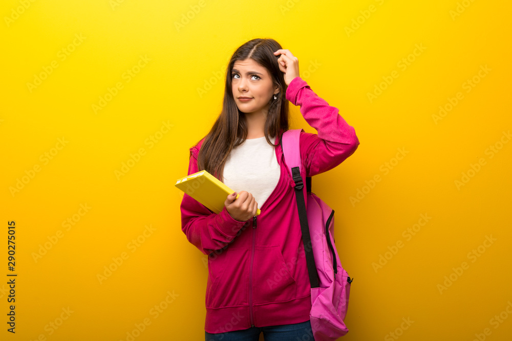 Teenager student girl on vibrant yellow background thinking an idea Teenager student girl on vibrant yellow background thinking an idea