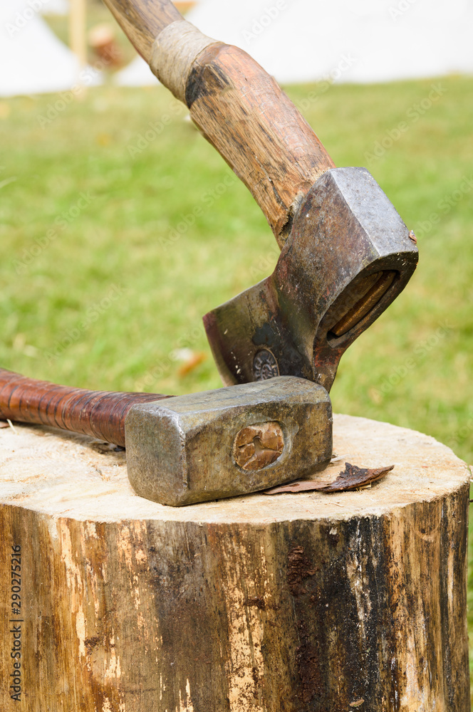 ax and hammer on a log on a background of green grass