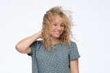 Cute curly blonde young model in studio with hair blown by wind