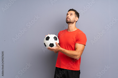 Handsome young football player man over isolated white wall looking up while smiling