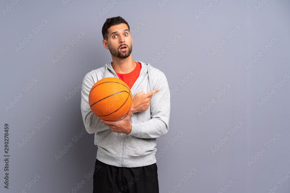 Handsome young basketball player man surprised and pointing side