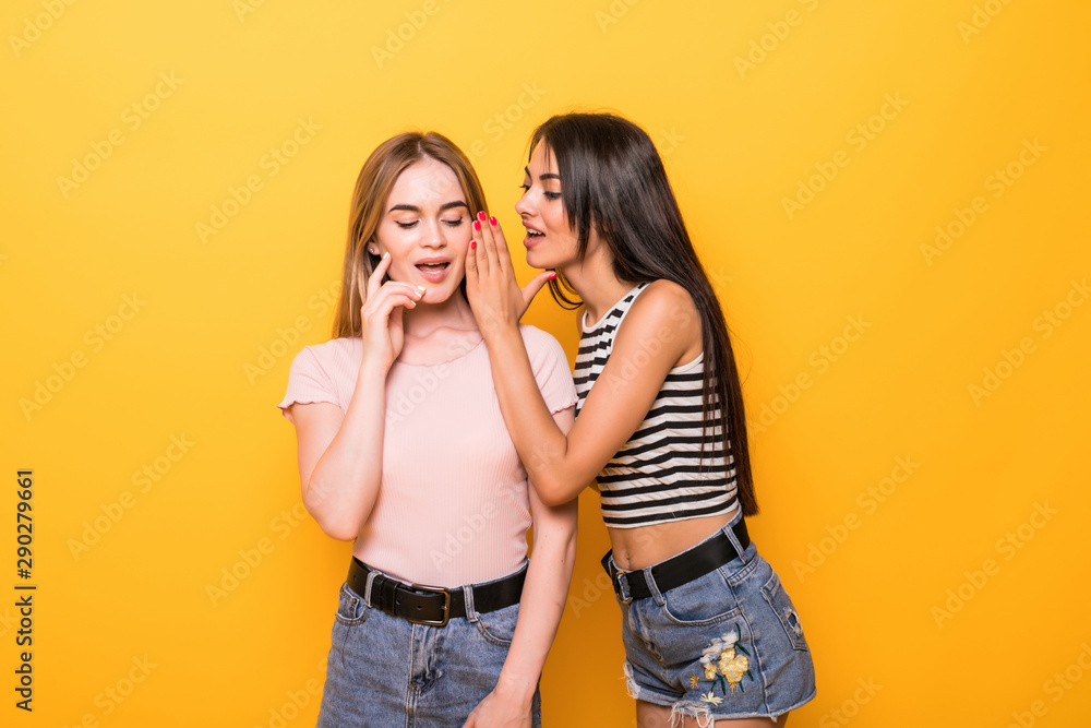 Portrait of two beautiful gossiping girls against orange background Portrait of two beautiful gossiping girls against orange background