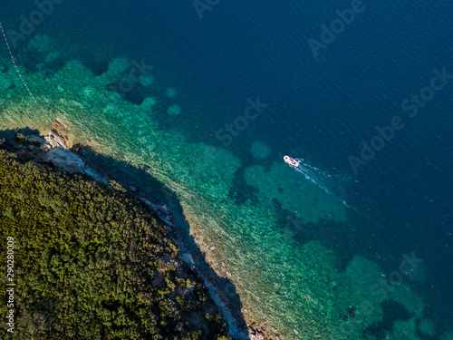 Aerial view of boats and watercraft off the coast of jagged and lush Mediterranean vegetation. Sea, crystal clear water. Sveti Nikola, Budva island, Montenegro
