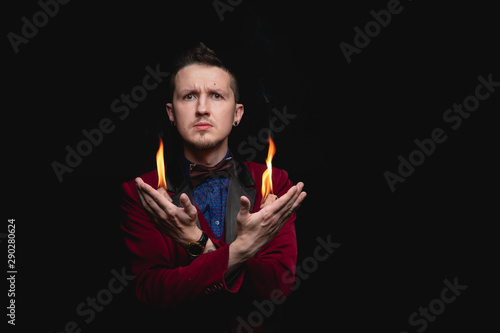 Focus with fire from palms hands shows magician on black background