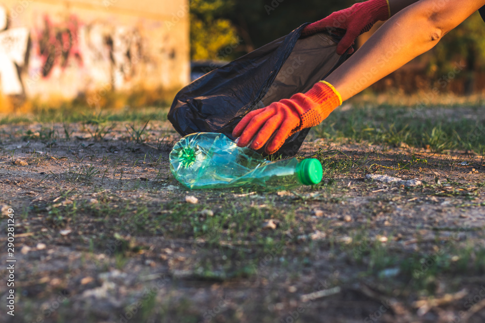 Garbage bottles picked up and thown into a trash bag. Plastic and food