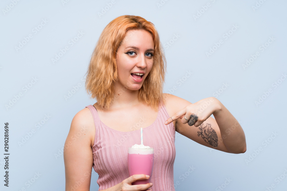 Young woman with strawberry milkshake over isolated blue background Young woman with strawberry milkshake over isolated blue background