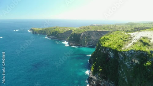 Drone Shot by drone Ocean with waves and rocky cliff Bali, Indonesia. Beautifulbeach of Kelingking in Nusa Penid. Aerial view of Big Blue Sea Wave viewpoint. photo