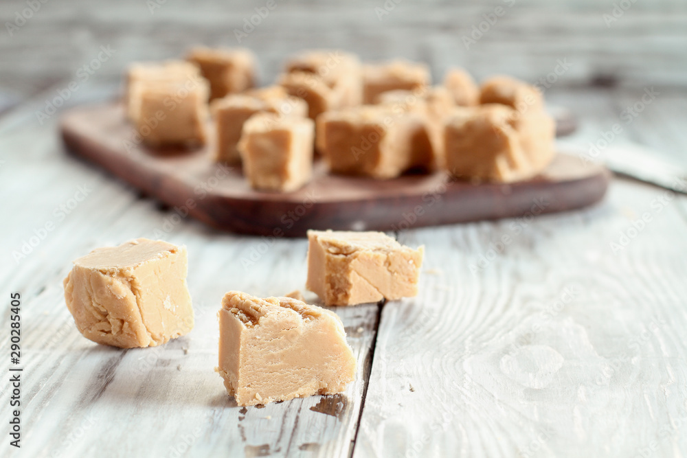 Squares of delicious, homemade peanut butter fudge over a rustic wood table. Selective focus on candy in the foreground with blurred background. Squares of delicious, homemade peanut butter fudge over a rustic wood table. Selective focus on candy in the foreground with blurred background.