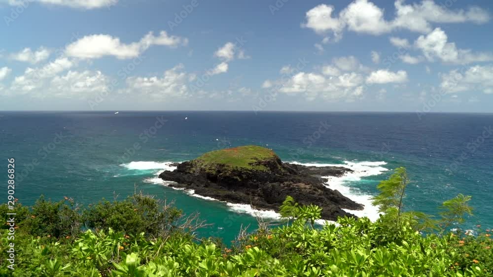 Private volcanic island off the coast with green vegetation Private volcanic island off the coast with green vegetation