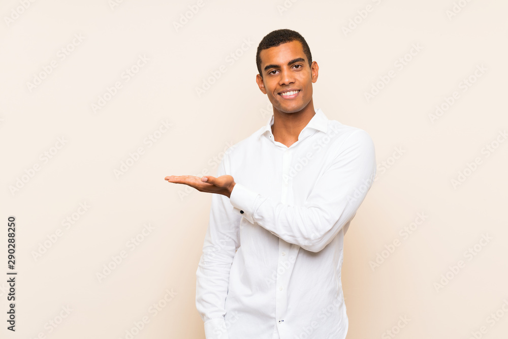 Young handsome brunette man over isolated background presenting an idea while looking smiling towards Young handsome brunette man over isolated background presenting an idea while looking smiling towards