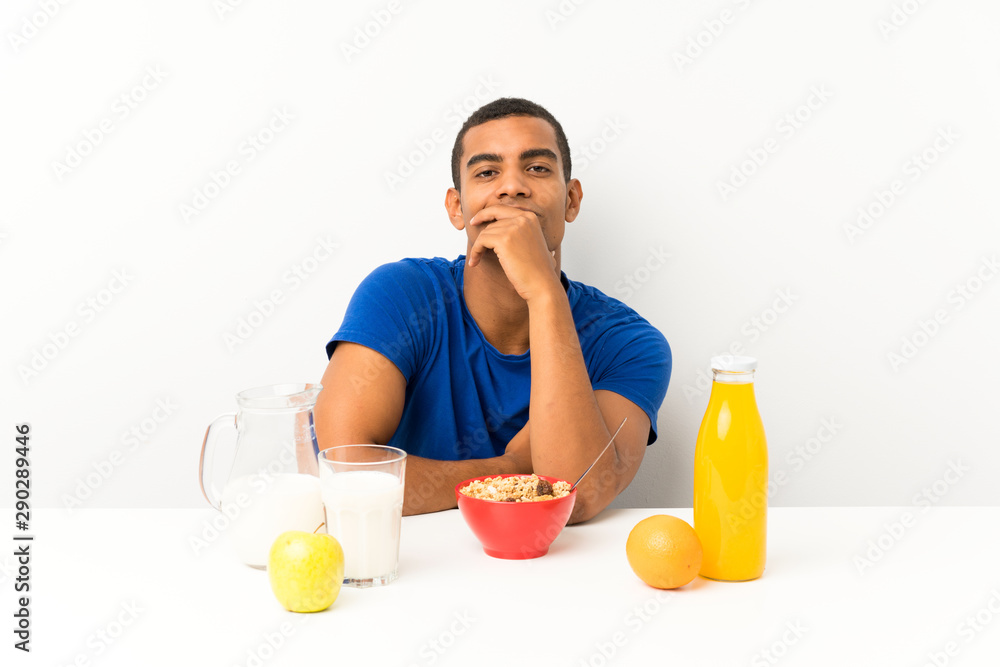 Young man having breakfast in a table laughing Young man having breakfast in a table laughing