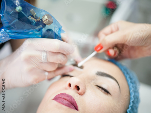 Decorative cosmetology courses. Female beautician using tattoo machine for eyebrow microblading.