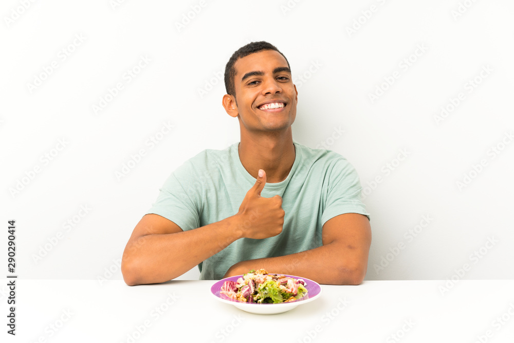 Young handsome man with salad in a table giving a thumbs up gesture Young handsome man with salad in a table giving a thumbs up gesture