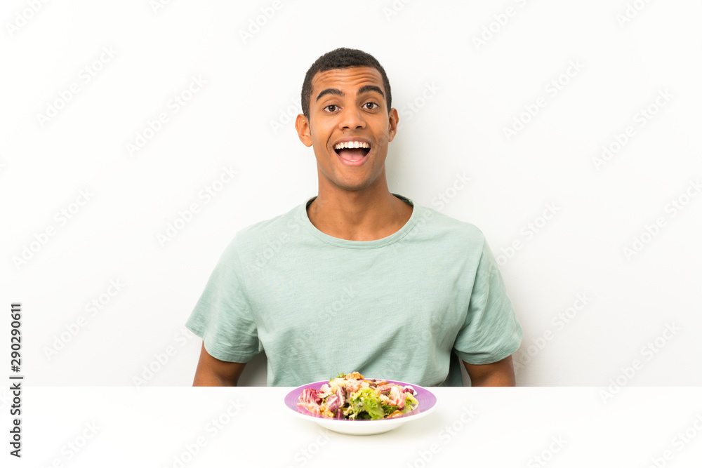 Young handsome man with salad in a table with surprise facial expression Young handsome man with salad in a table with surprise facial expression