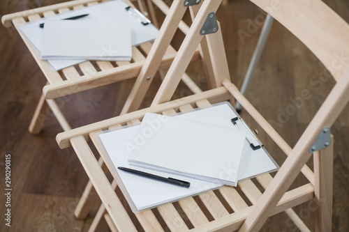 Art school. Creativity and inspiration. White blank mockup paper, sketchboards and pens on wooden chairs.