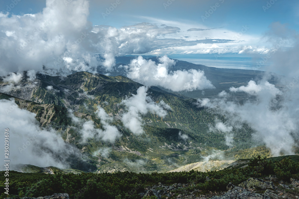 Beautiful view of the mountains from the peak. Landscape with clouds and stones at sunset. Concept climbing and Hiking