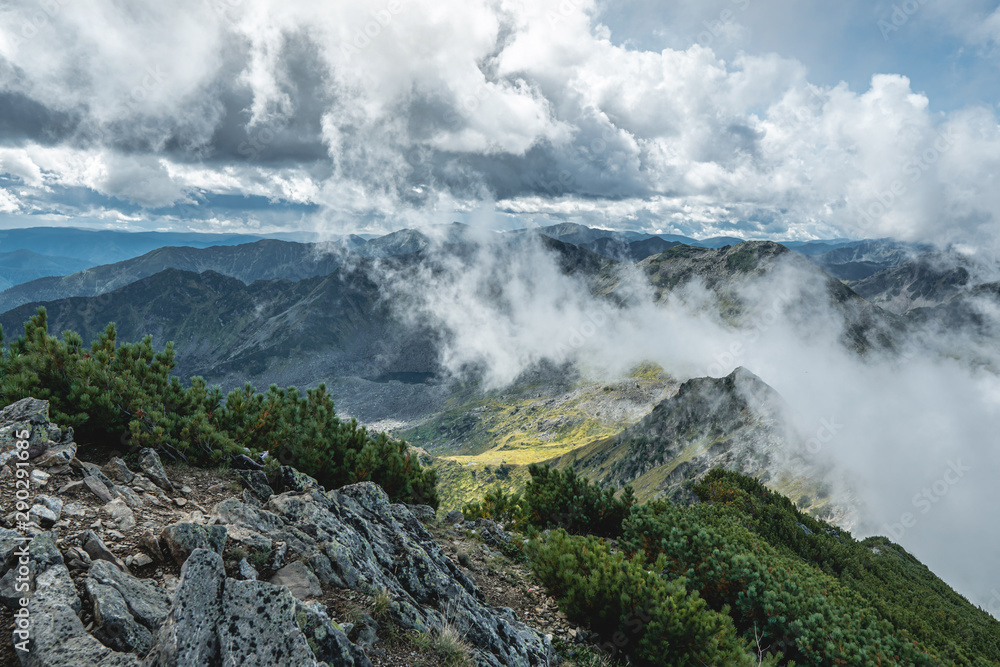 Beautiful view of the mountains from the peak. Landscape with clouds and stones at sunset. Concept climbing and Hiking Beautiful view of the mountains from the peak. Landscape with clouds and stones at sunset. Concept climbing and Hiking