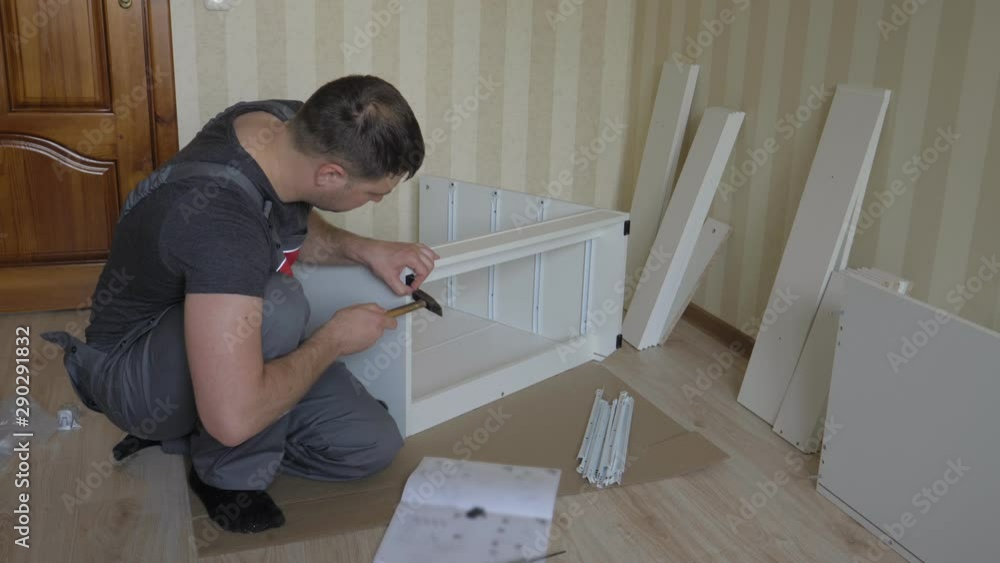 Worker On Assembly Of Furniture Strikes With Hammer The Nails Attaching Hardware Worker On Assembly Of Furniture Strikes With Hammer The Nails Attaching Hardware