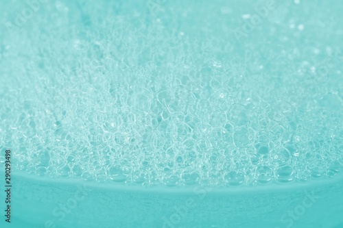 Soap bath bubbles on turquoise background. Laundry detergent, suds textured pattern. White soap suds macro view, copy text. Abstract background textured effect of blue soap foam close-up.
