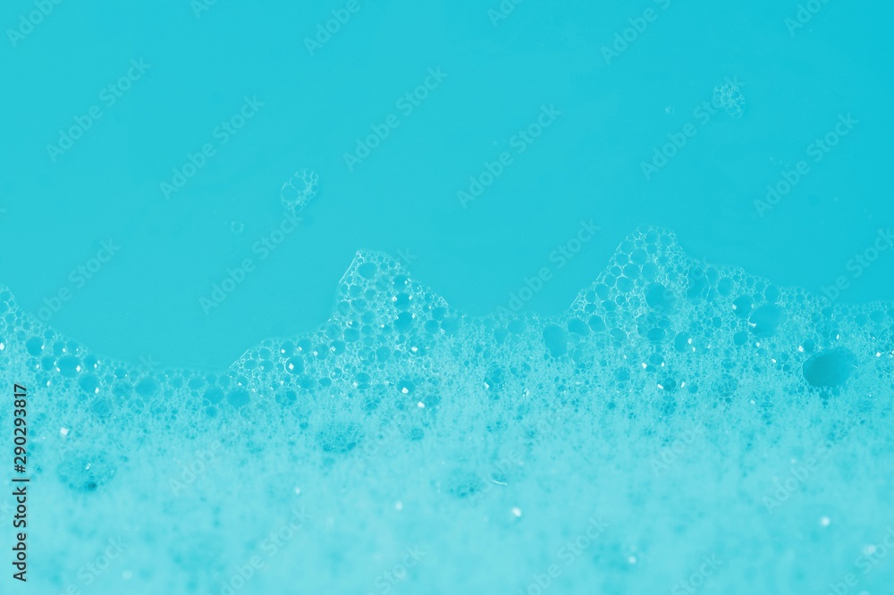 Soap bath bubbles on blue background. Laundry detergent, suds textured pattern. White soap suds macro view, copy text. Abstract background textured effect of blue soap foam close-up.