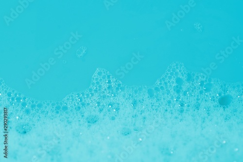 Soap bath bubbles on blue background. Laundry detergent  suds textured pattern. White soap suds macro view  copy text. Abstract background textured effect of blue soap foam close-up.