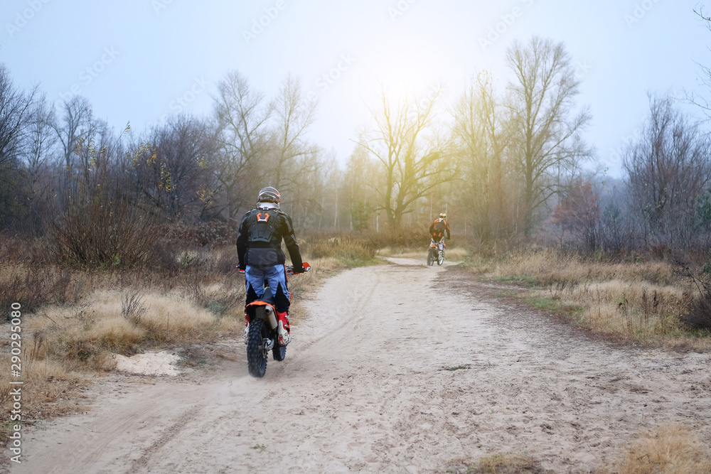 Sport and active healthy life concept. Motorcyclist in protective in late fall park. Riding on motorcycle on sunny day among trees. Healthy lifestyle.