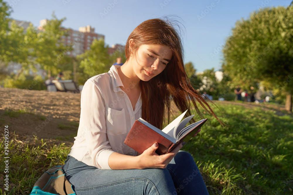 Obraz premium Pretty Caucasian student reads notes in city park
