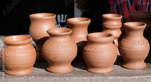 Potter-shaped pots prepared for baking in an oven stand on the table.