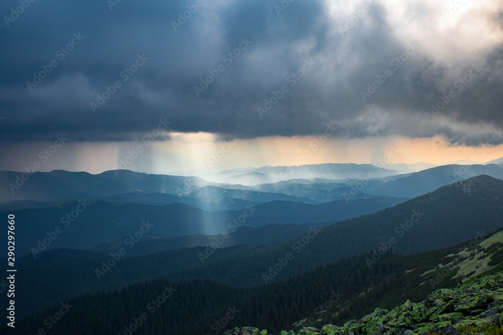 sun ray through thunderstorm clouds in the mountains